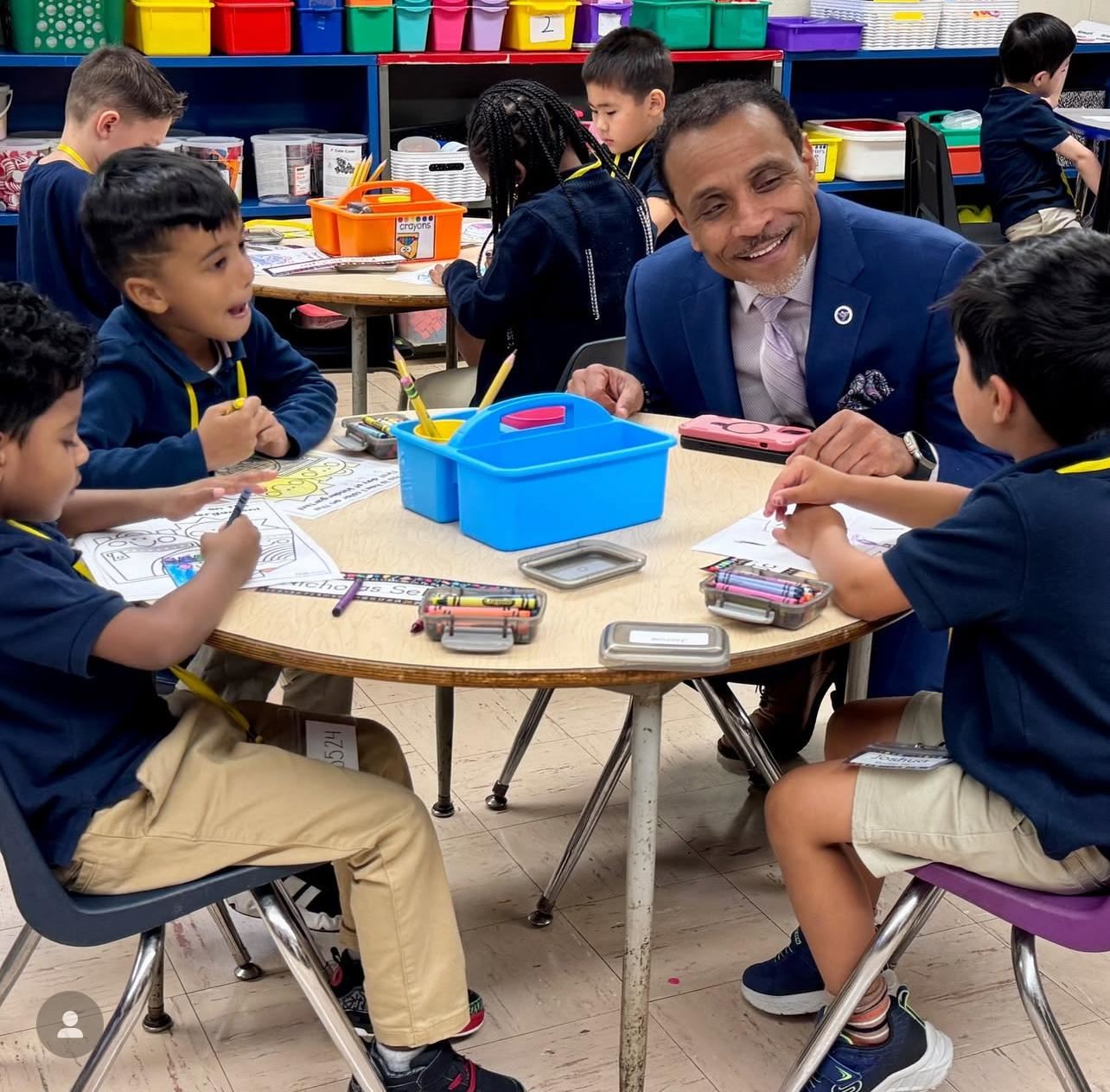 School District of Philadelphia Superintendent, Tony Watlington sitting wtih students in a classroom.